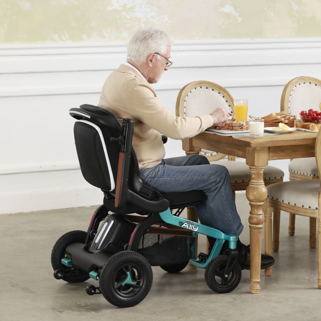 Golden Ally Power Wheelchair Teal with man sitting at table eating