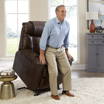 Man sitting on a brown leather list chair recliner in a living room.